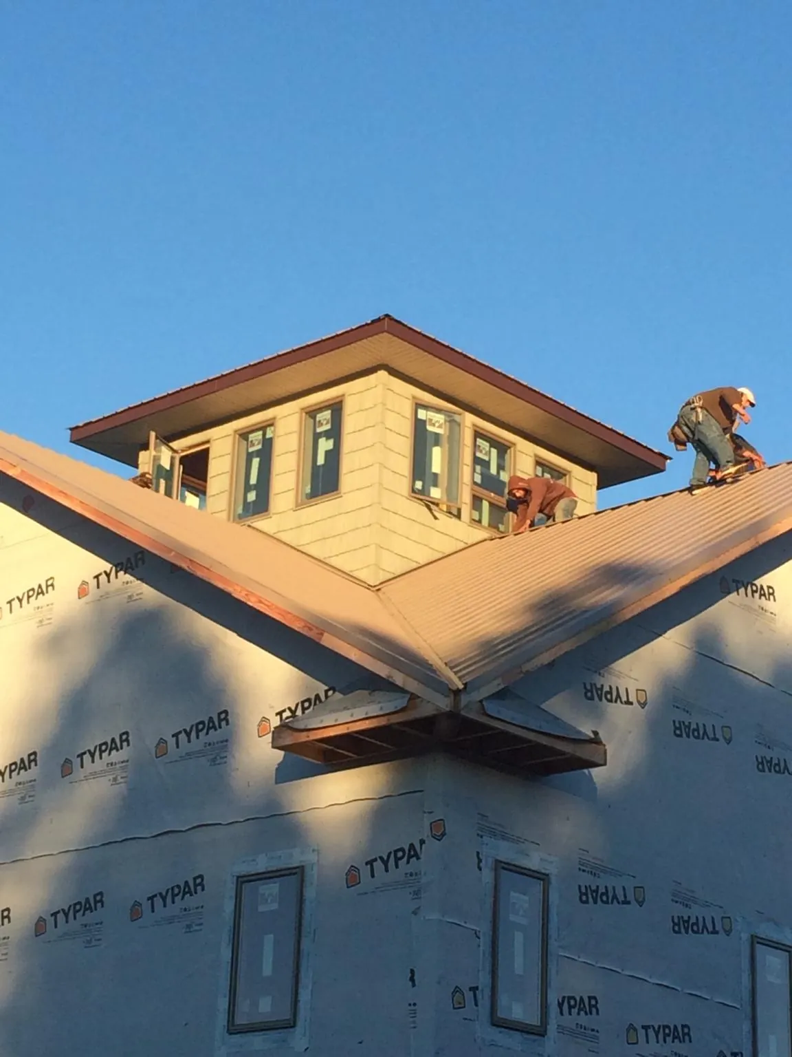 Roofers working around a rooftop cupola on a new metal roof at sunset — Roof Waterproofing in Marietta by Roofing Brothers